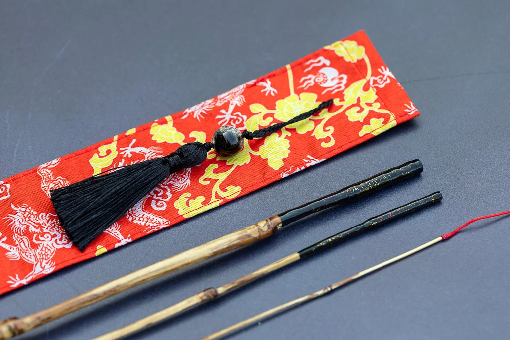 Hand-built 1.78 meter bamboo Tanago rod for micro-fishing, featuring a sculpted ergonomic artisan handle and a red dragon-patterned fabric protector, handcrafted in Spain.