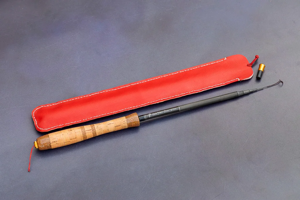 Close up of Mario Diaz signature on a Tenkara Graphite 44 fly fishing rod with cork handle and red leather case